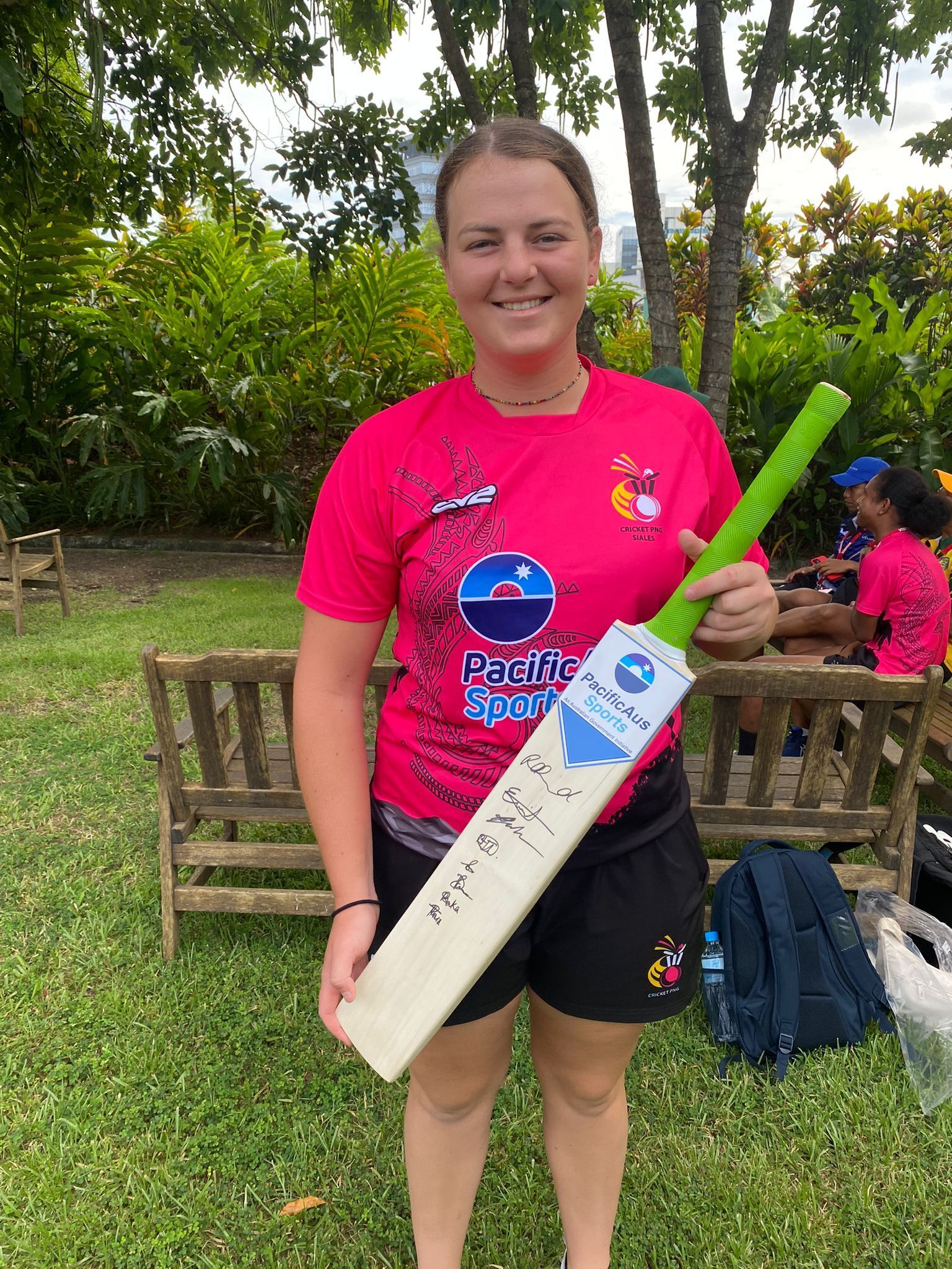 Ellie Johnston with a cricket bat signed by the Australian players and PNG team captains